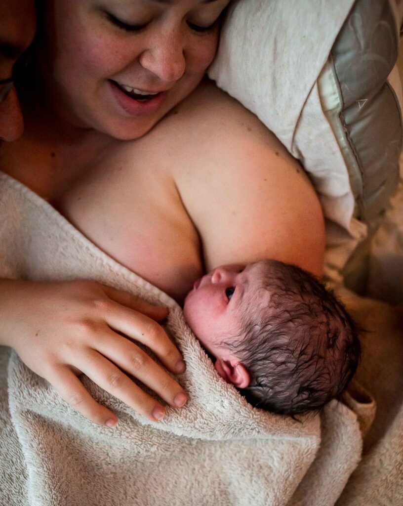dani gazes adoringly at her darling baby girl who is her fifth and final child. She closes a chapter in her life during her longest and most arduous birth at home during the pandemic