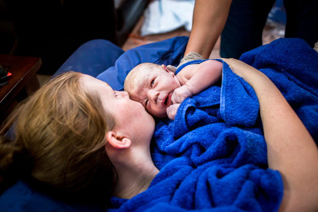 mother kissing baby after home birth