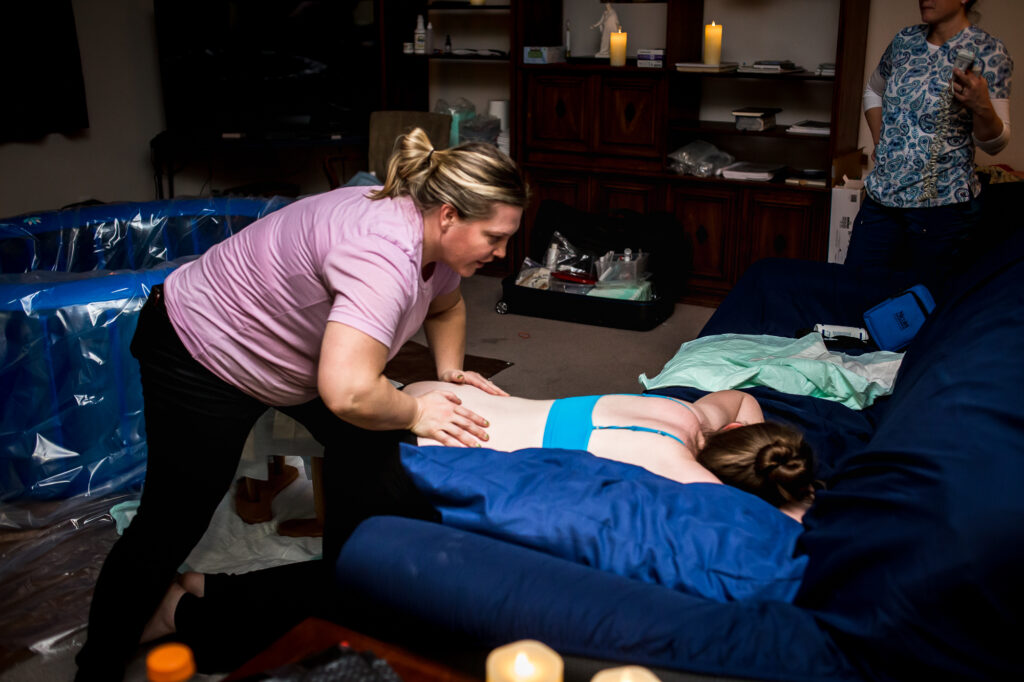 Doula Sarah provides counter pressure as Alisa works through a contraction at her home birth in lehi, Utah