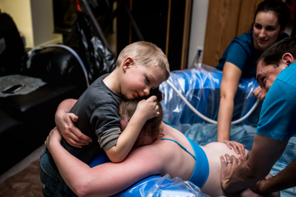 Soon to be big brother gives mom Alisa a hug as she works through a contraction at her home birth in lehi, utah