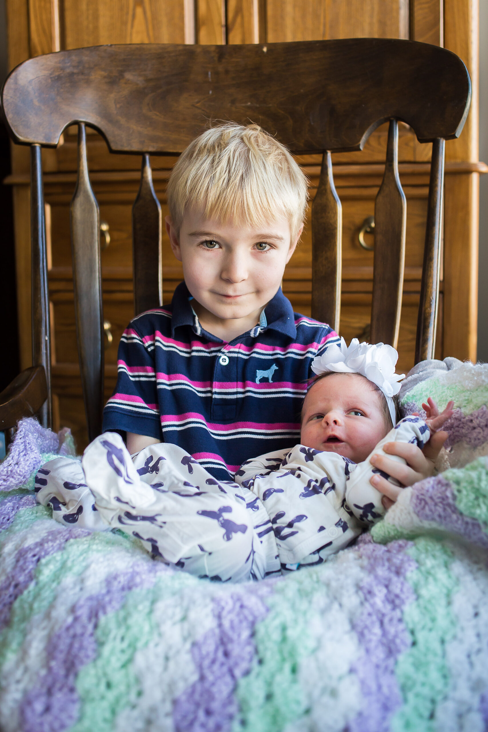 Big brother David smiles as he proudly holds his new baby sister at their newborn session in Mapleton.