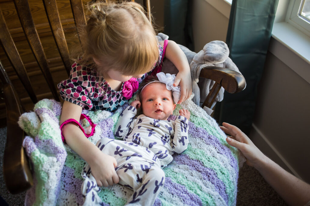 Newly made big sister Charlotte takes her turn holding baby Sarah during pictures during a newborn session in Mapleton